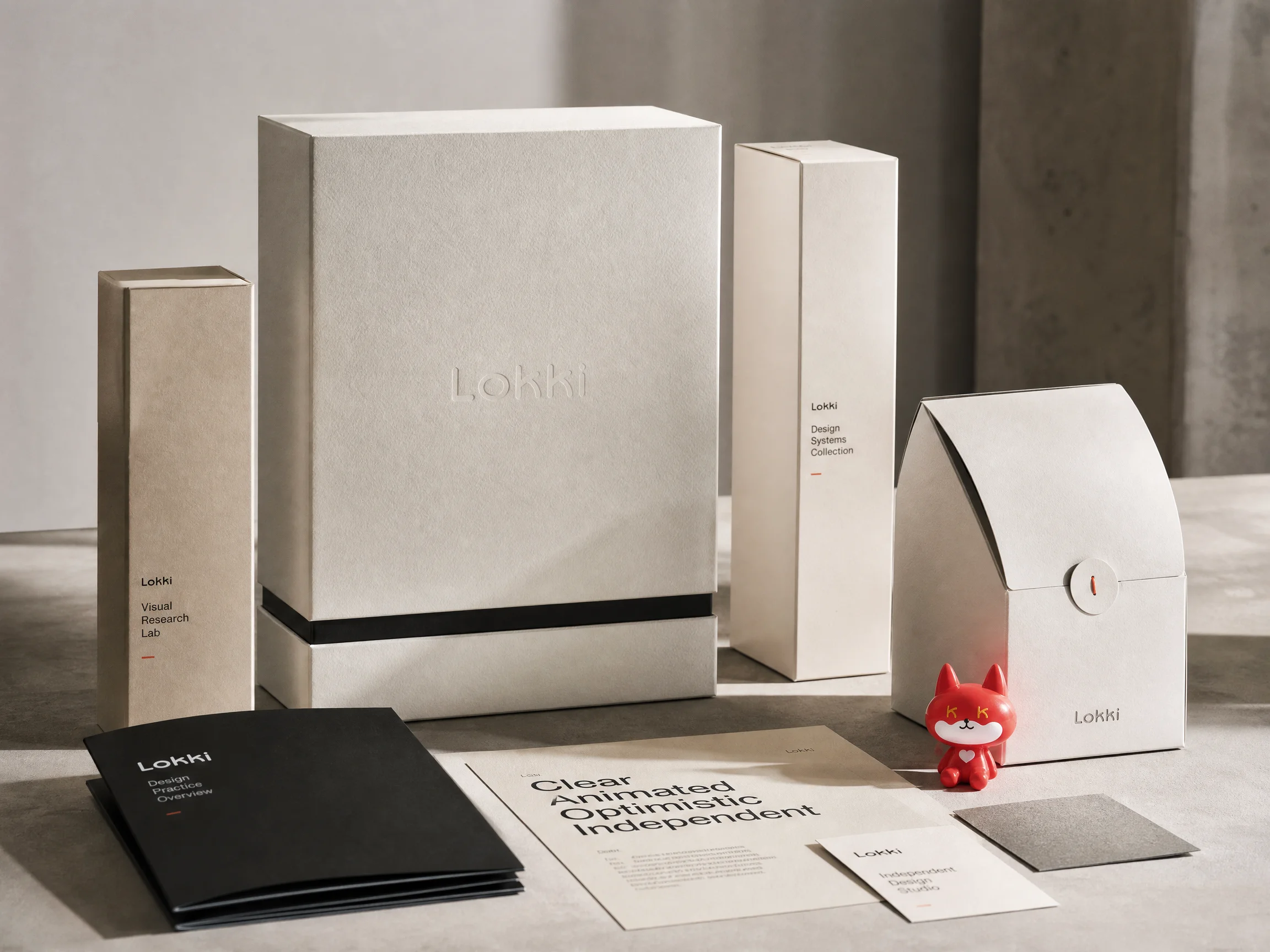 Premium packaging prototypes, identity materials, print pieces, and a LOKKI character object arranged in the studio.